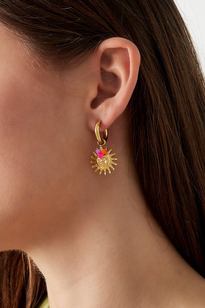 Close-up side view of gold sun hoop earrings with pink and orange beads on a woman with dark brown hair