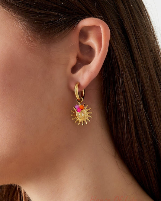 Close-up side view of gold sun hoop earrings with pink and orange beads on a woman with dark brown hair