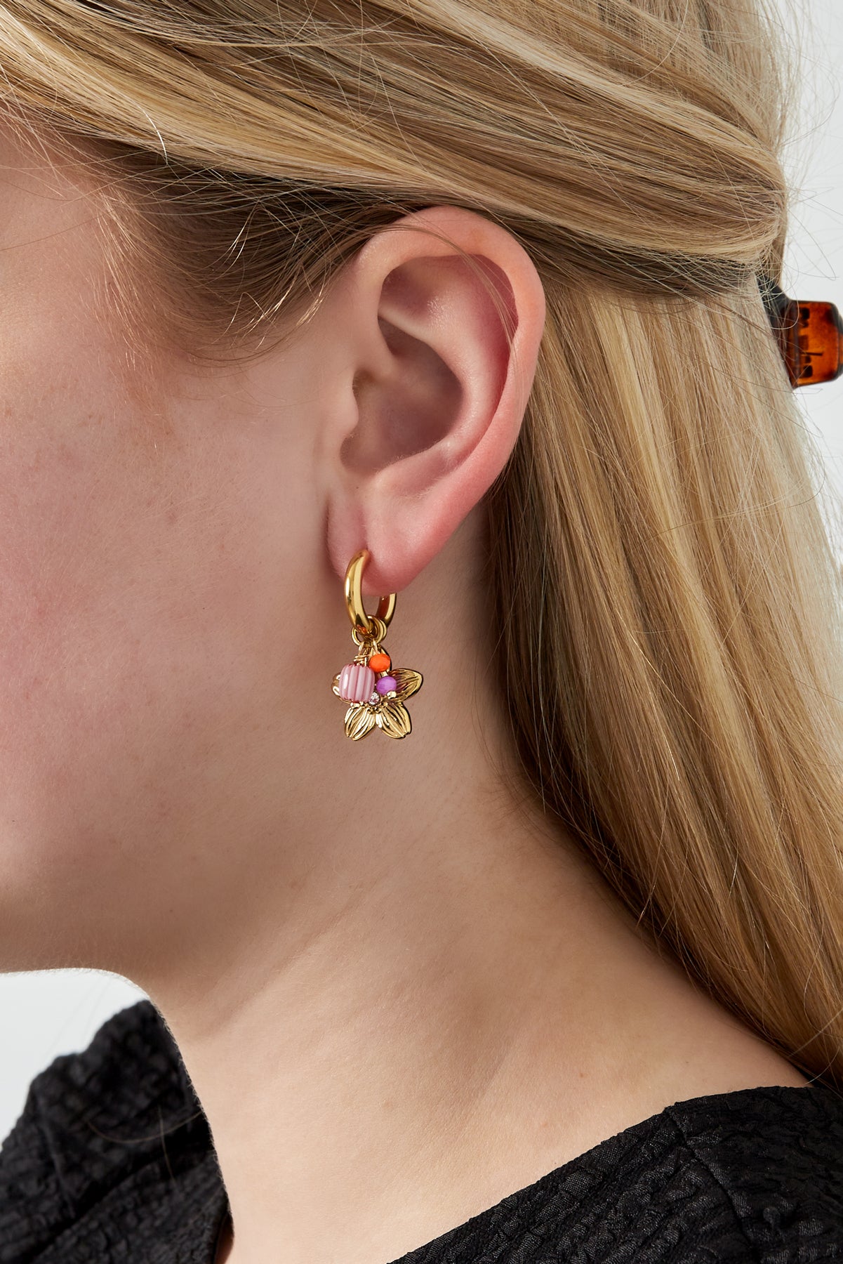 Model wearing gold-tone floral charm hoop earring with colourful beads, showcasing a youthful and minimal style