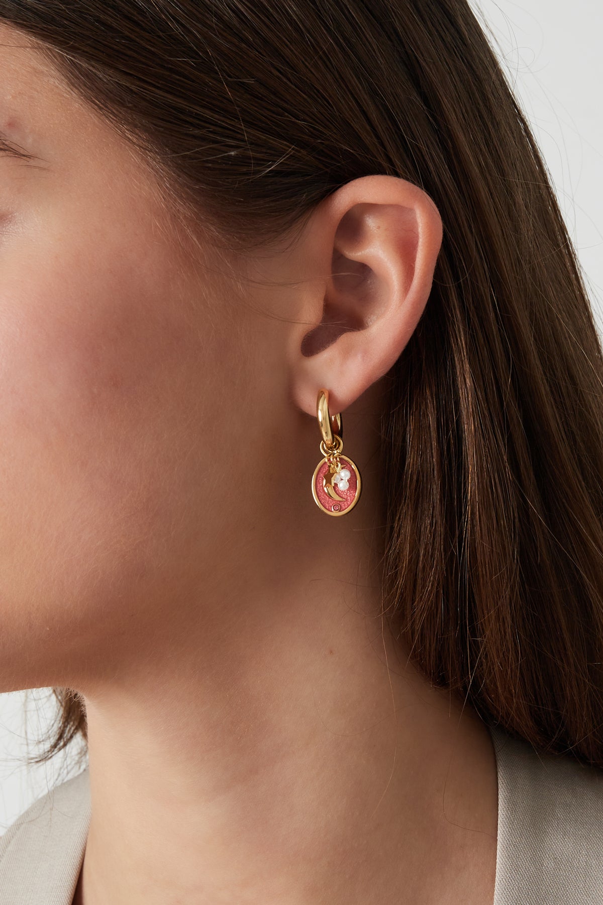 Close-up of a woman wearing the gold-tone celestial charm hoop earring showcasing crescent moon, star, and pearl details