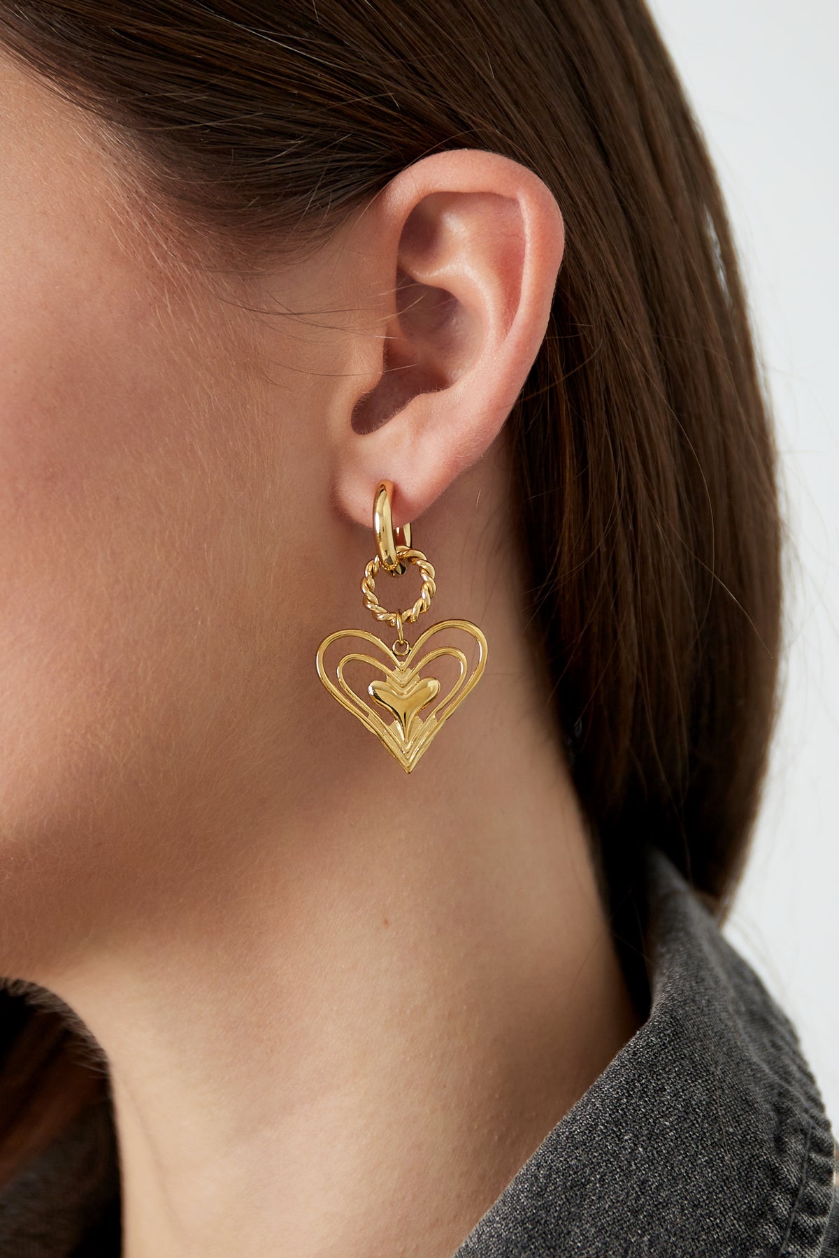 Model wearing gold twisted heart drop earrings showing side profile
