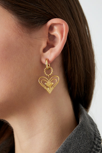 Model wearing gold twisted heart drop earrings showing side profile