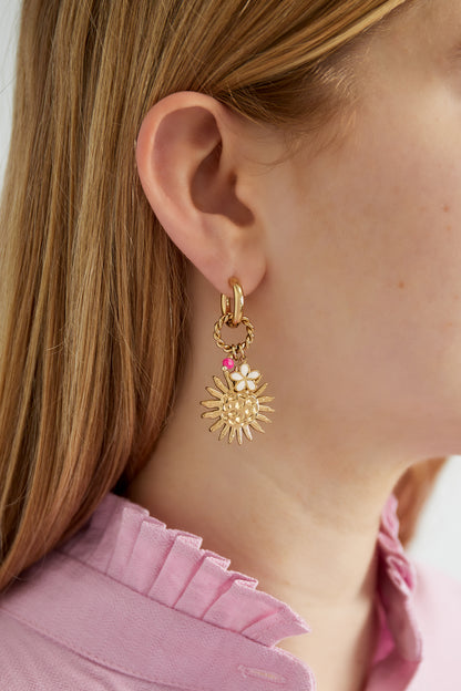 Close-up of model wearing gold-tone sunshine charm drop earring with white flower and pink bead detail, paired with a pink ruffled shirt.