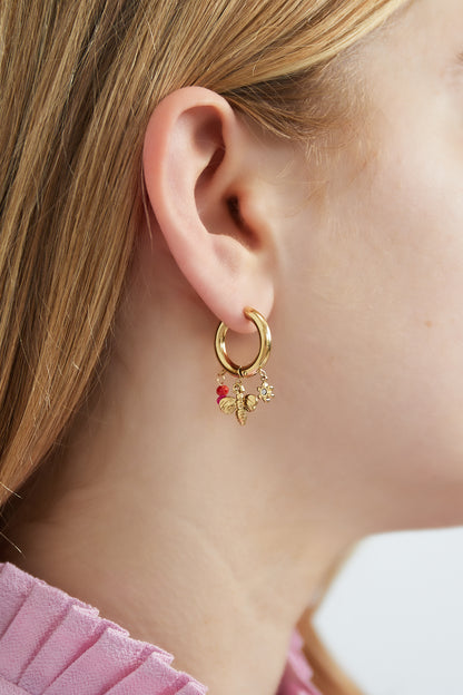 Model wearing gold charm hoop earring with bee, flower and red-pink beads