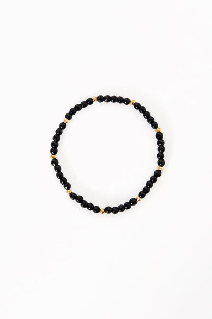 Black and gold beaded bracelet laid flat on white background showcasing small glossy black beads and gold accent beads