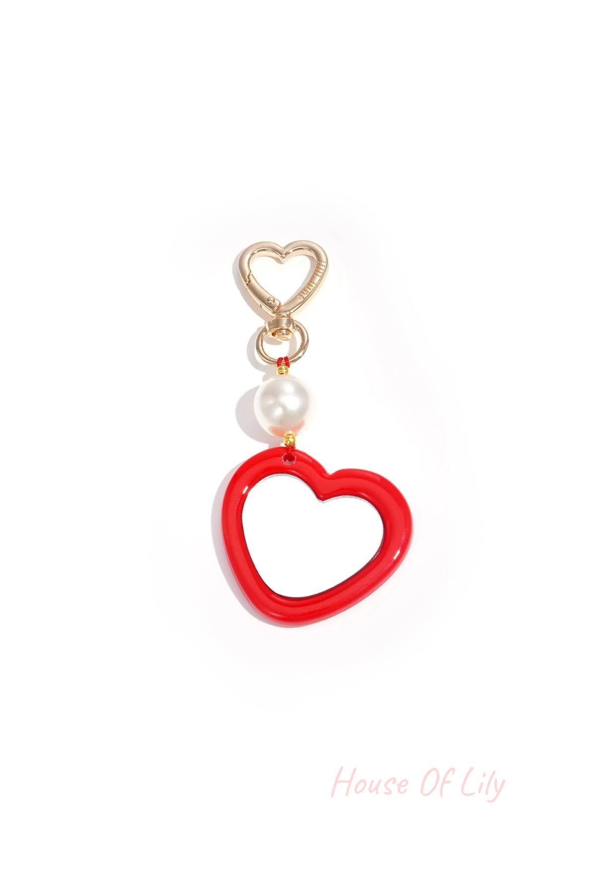 Close-up of gold heart-shaped clip holding red acrylic heart charm with pearl bead
