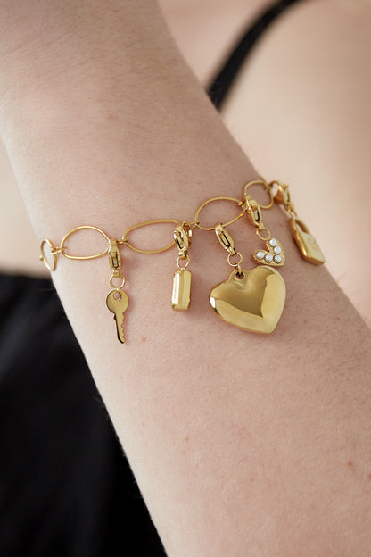 Close-up of the golden charm bracelet on a woman's arm highlighting the details of the charms and link design