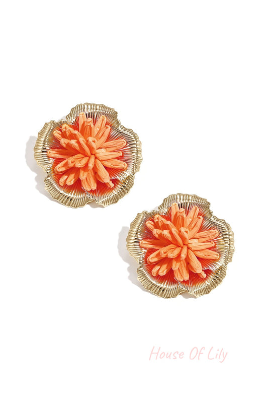 Pair of vibrant orange 3D raffia flower stud earrings with gold-tone metal frame on white background