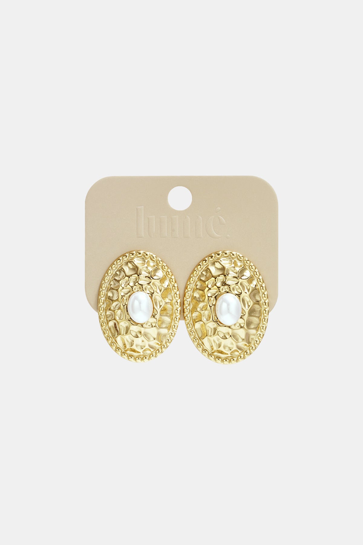 Gold-tone oval stud earrings with hammered texture and pearl center attached to beige Lumé branded card