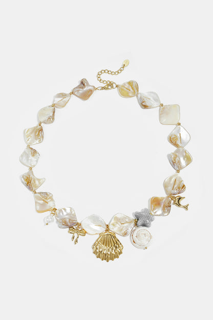 Close-up of a sea shell charm necklace with mother-of-pearl beads and gold-tone shell, bow, starfish, dolphin, and pearl charms displayed on white background