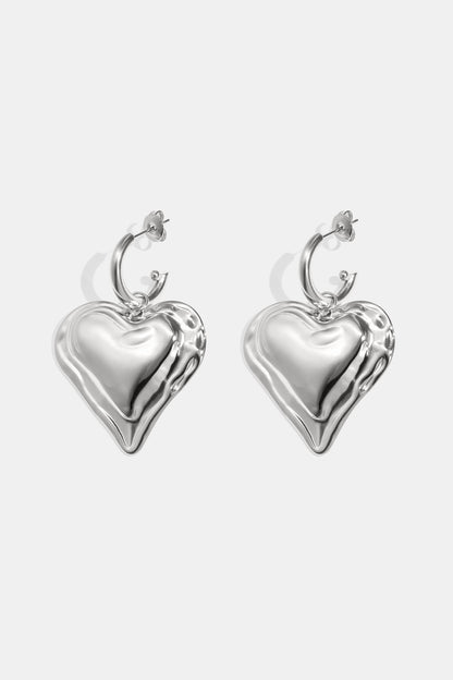 Close-up of chunky silver heart hoop earrings with rippled textured heart charms on white background