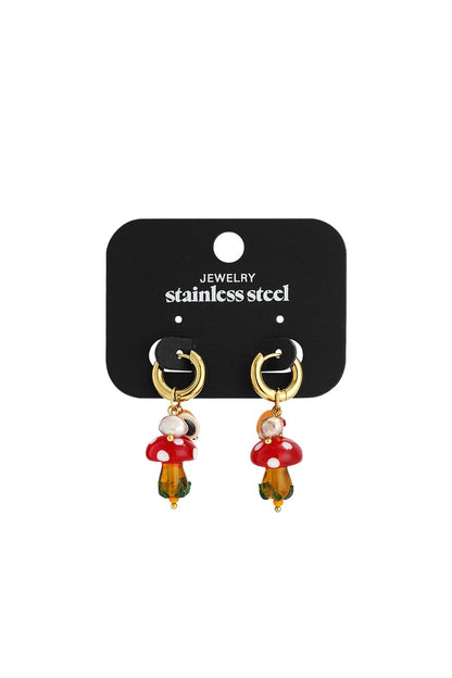 Gold stainless steel hoop earrings featuring dangling red-and-white mushroom charms with beads on a display card.