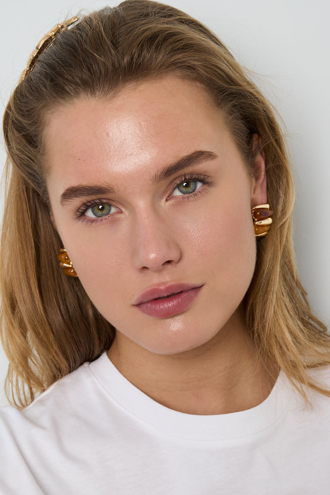 Jelly Bubble Hoops: Gold-tone chunky hoop earrings featuring amber-colored resin segments, worn by a woman.