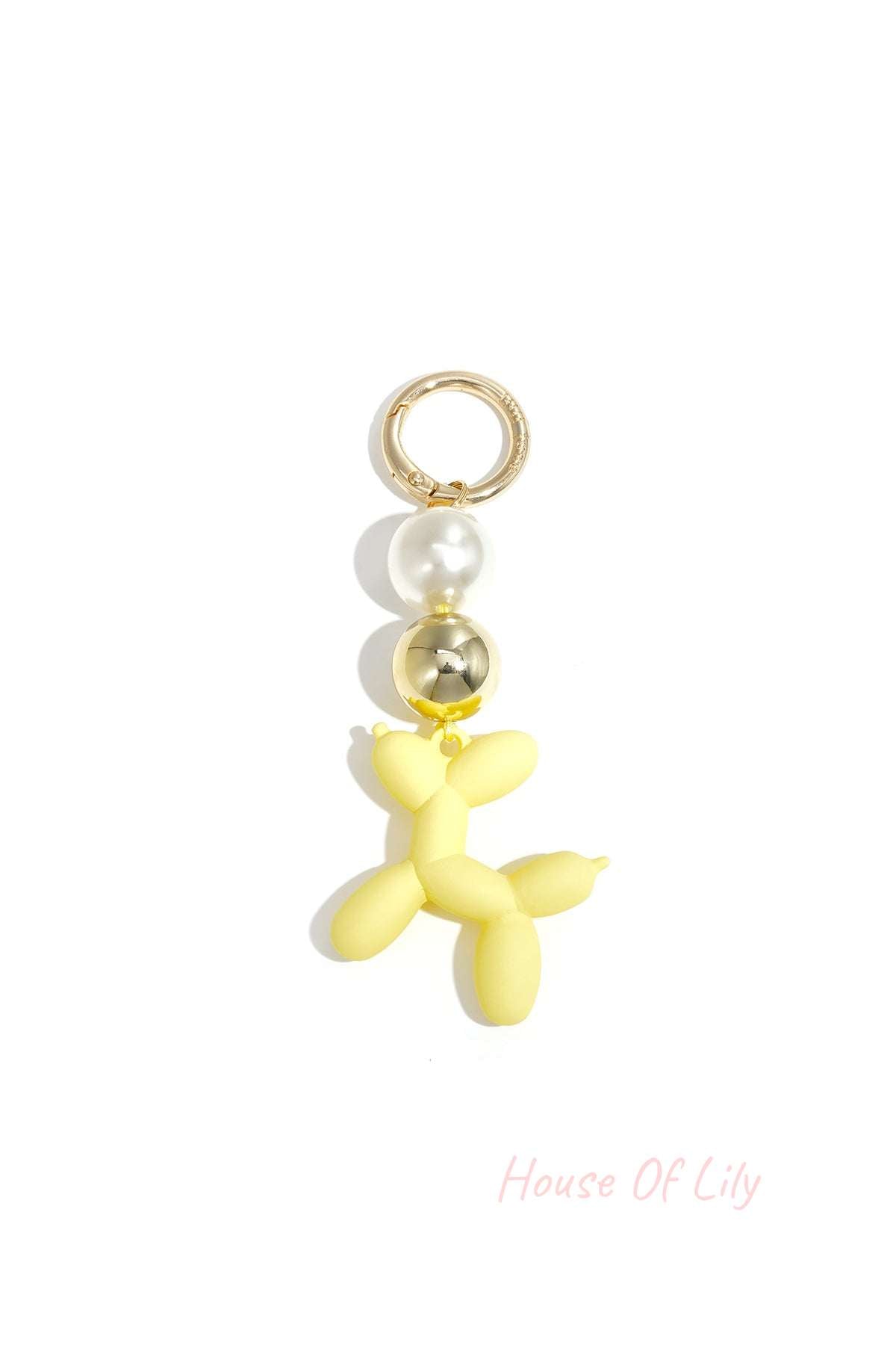 Yellow balloon dog bag charm with pearl and gold beads on white background
