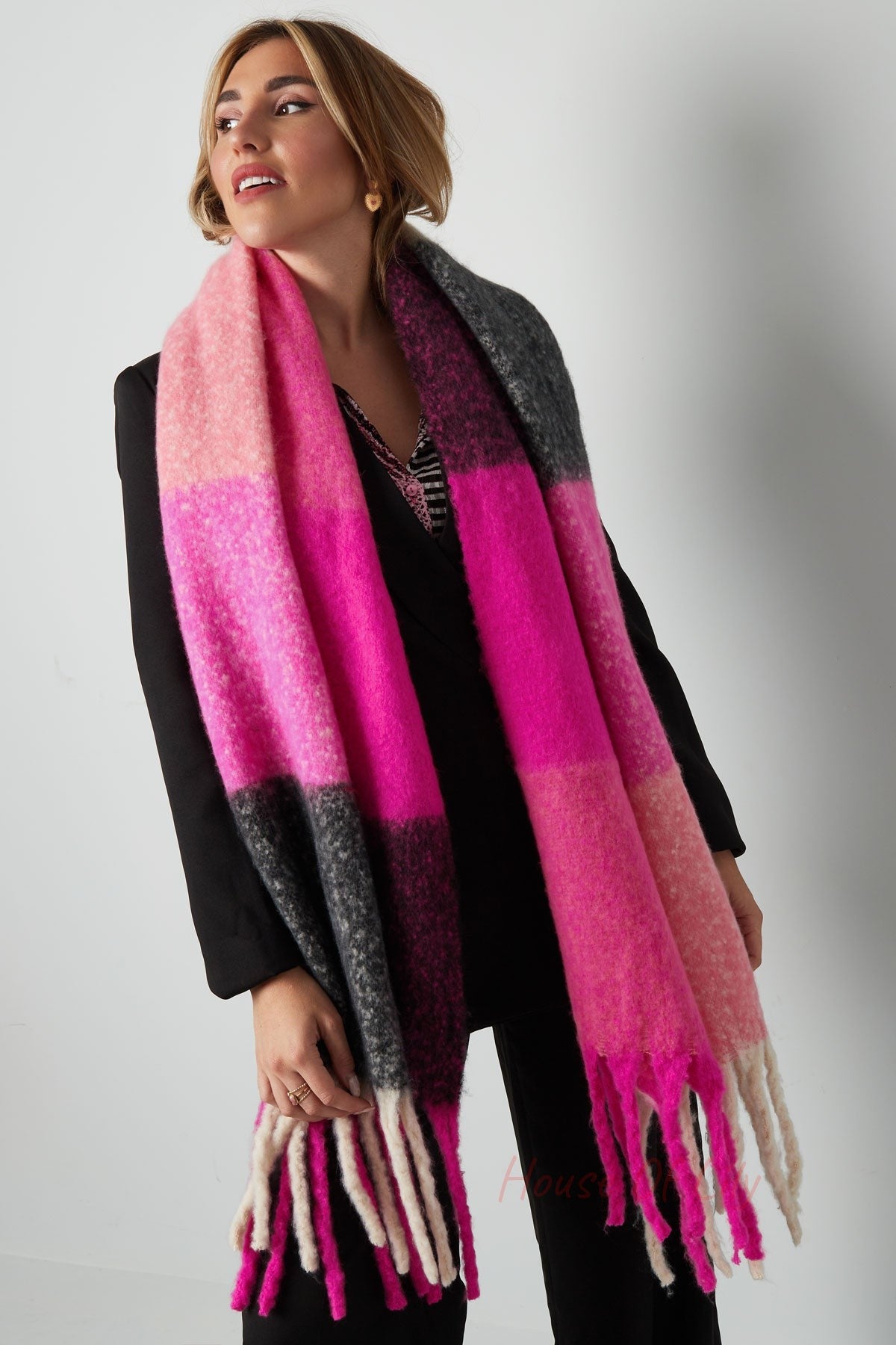 Close-up of woman wearing the bright pink and grey colorblock scarf showing its soft texture and tassel details