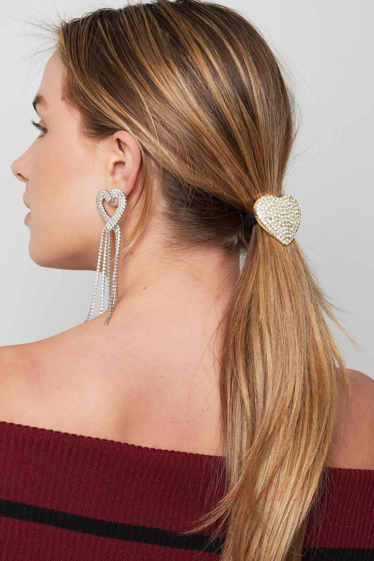 Model wearing the heart crystal hair elastic in her ponytail paired with long dangling crystal heart-shaped earrings and off-shoulder top