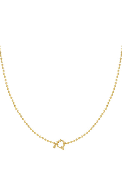 Close-up of a gold bead chain necklace with circular toggle clasp on white background