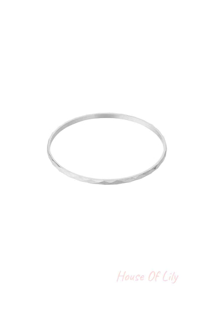 Single silver facet textured bangle bracelet on white background