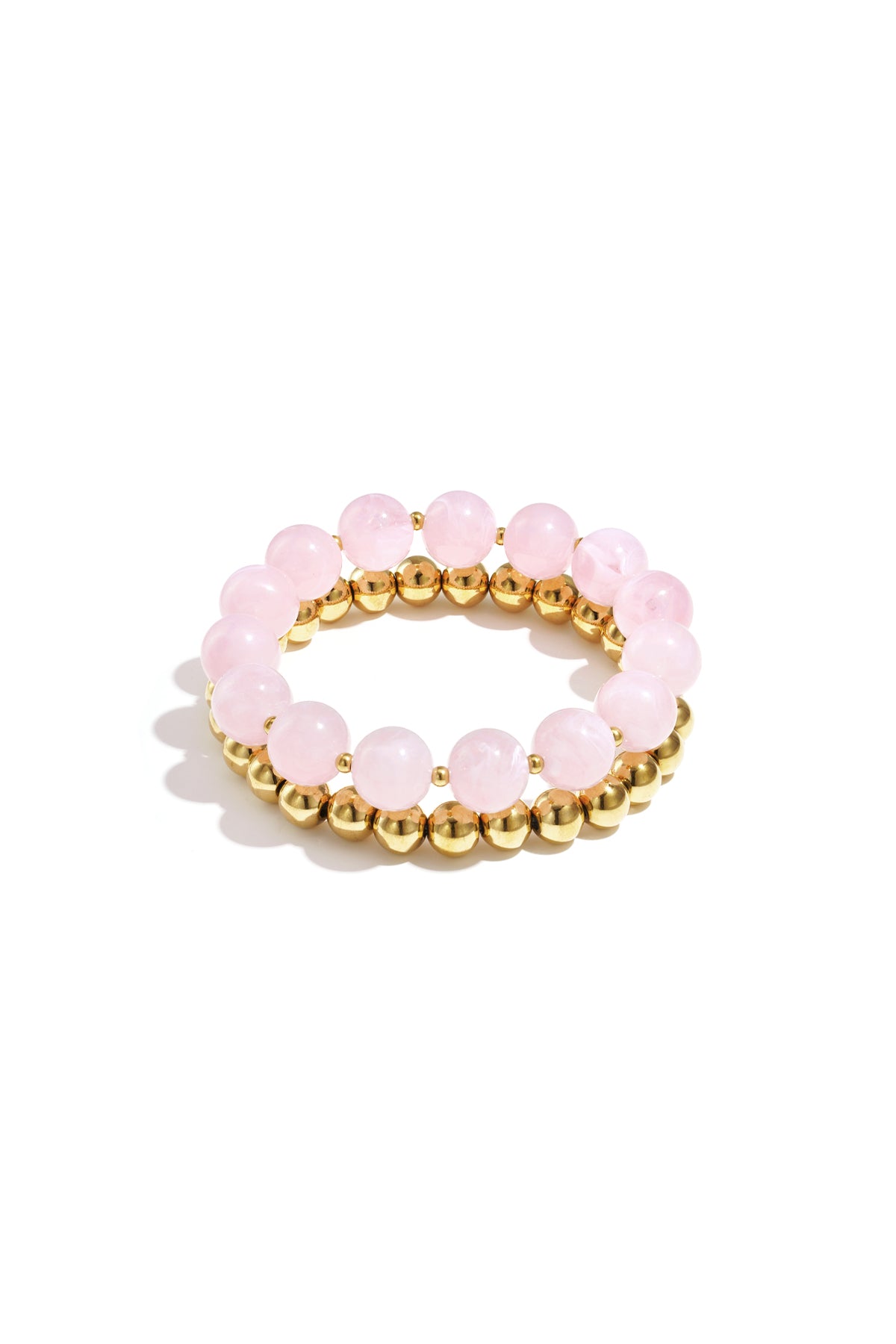 Stack of two bracelets with soft pink round acrylic beads and gold-tone metal beads on white background