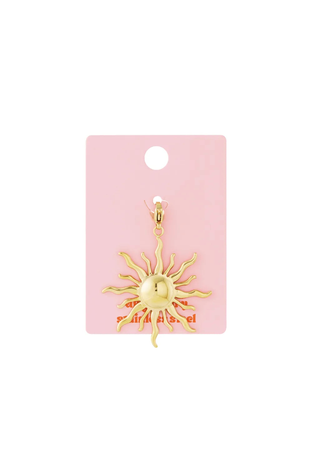 Shiny gold sun jewelry charm with wavy rays, attached to a lobster clasp on pink backing.