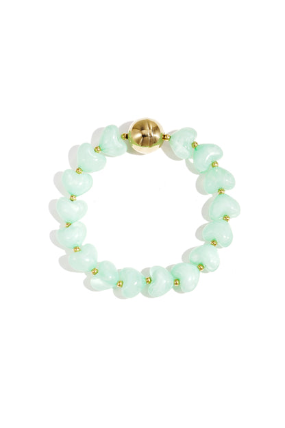 Mint green heart-shaped acrylic beaded bracelet with gold bead accent on white background