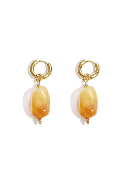 Gold hoop earrings with irregular orange resin drop beads on white background