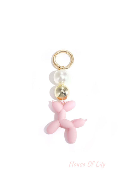 Soft pink balloon dog bag charm with pearl and gold beads on white background