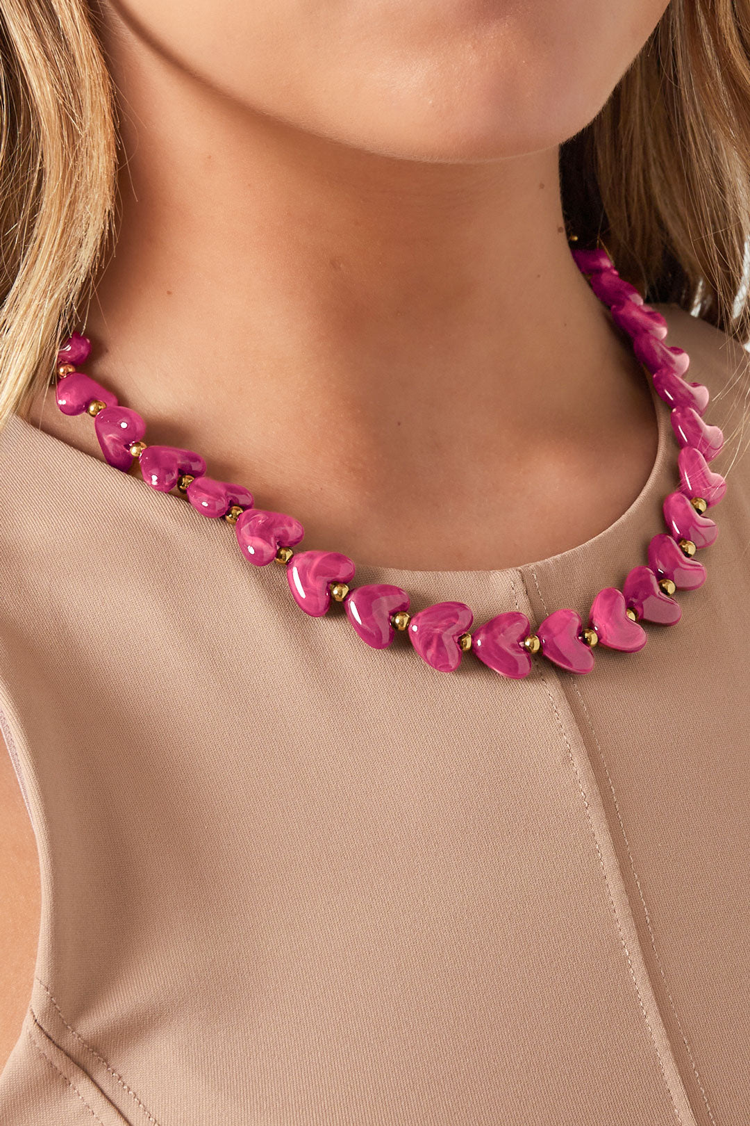Close up of woman wearing vibrant pink heart bead necklace