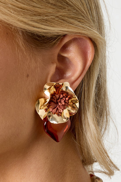 Close-up of model’s ear wearing warm brown floral heart drop earring with gold flower and resin heart