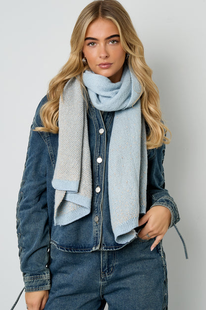 Model wearing the light blue colorblock sparkle scarf draped around her neck over denim jacket