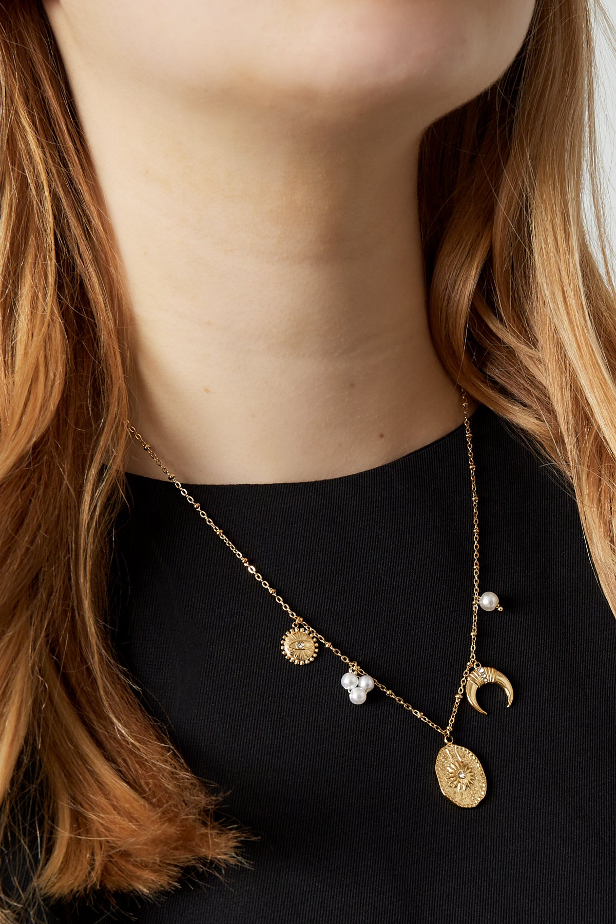 Close-up of celestial charm pendant necklace on model wearing black top showing length and charm details