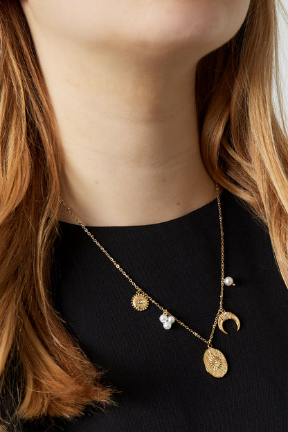Close-up of celestial charm pendant necklace on model wearing black top showing length and charm details