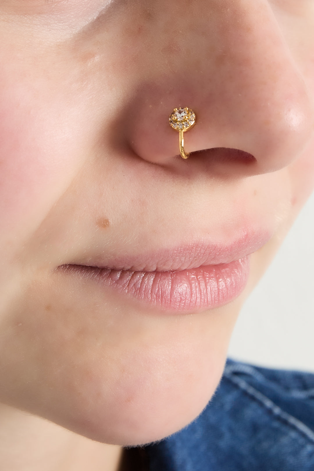 Close-up of a woman wearing a gold cubic zirconia ear and nose cuff on her nostril