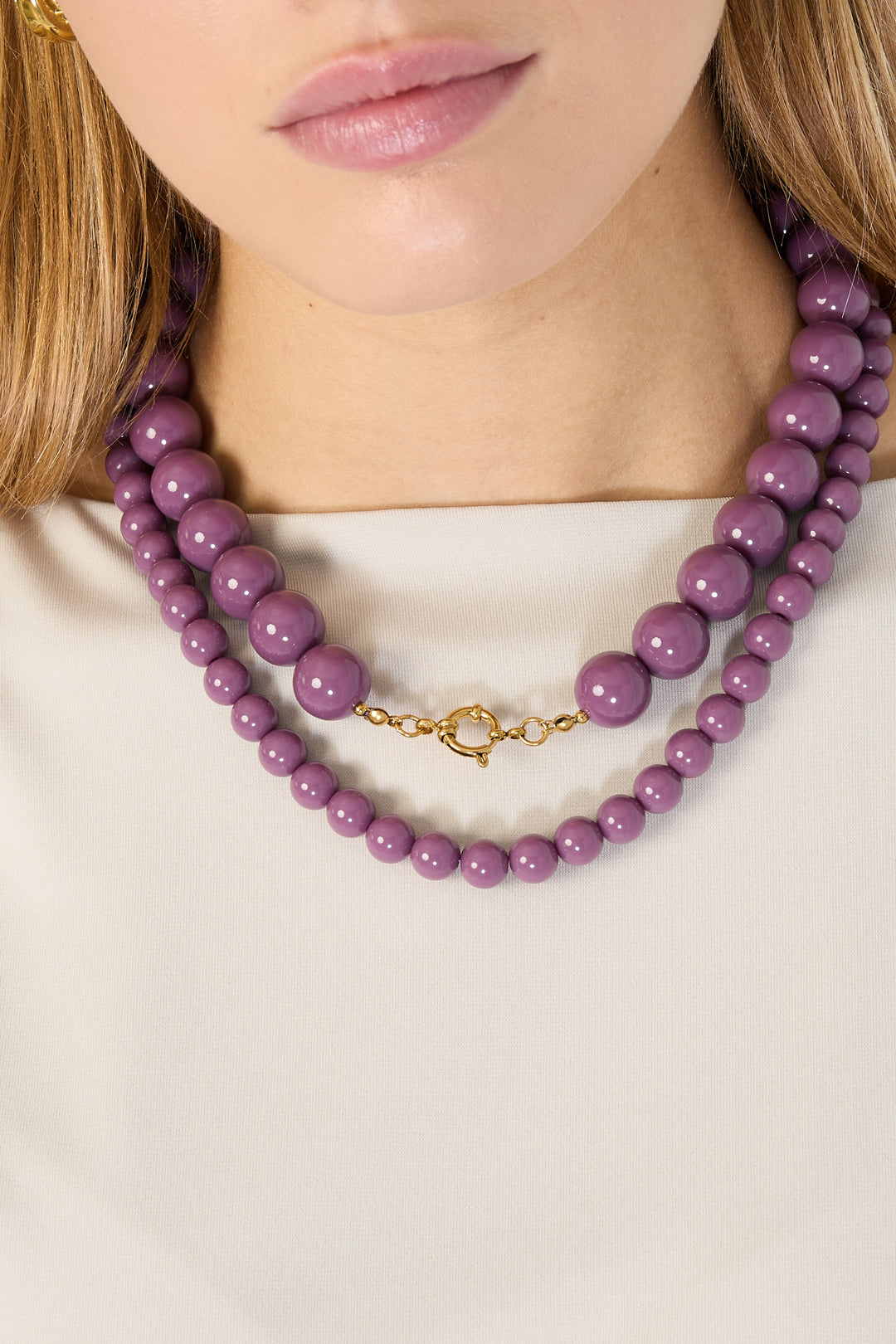 Pink resin beaded necklace with gold chain extender and lobster clasp on white background