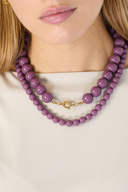 Pink resin beaded necklace with gold chain extender and lobster clasp on white background