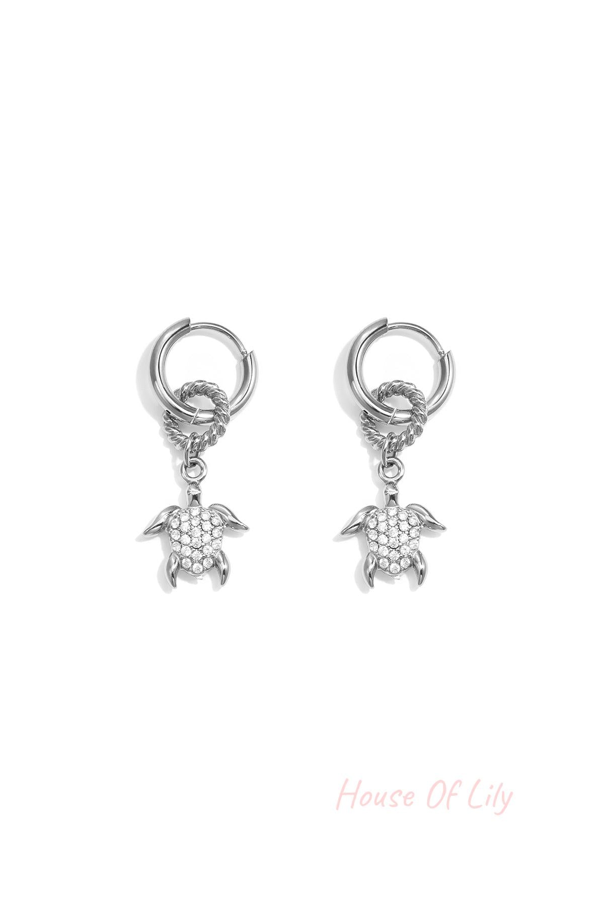 Silver hoop earrings with a textured ring and a dangling pavé turtle charm.