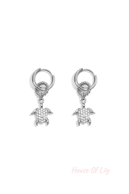 Silver hoop earrings with a textured ring and a dangling pavé turtle charm.