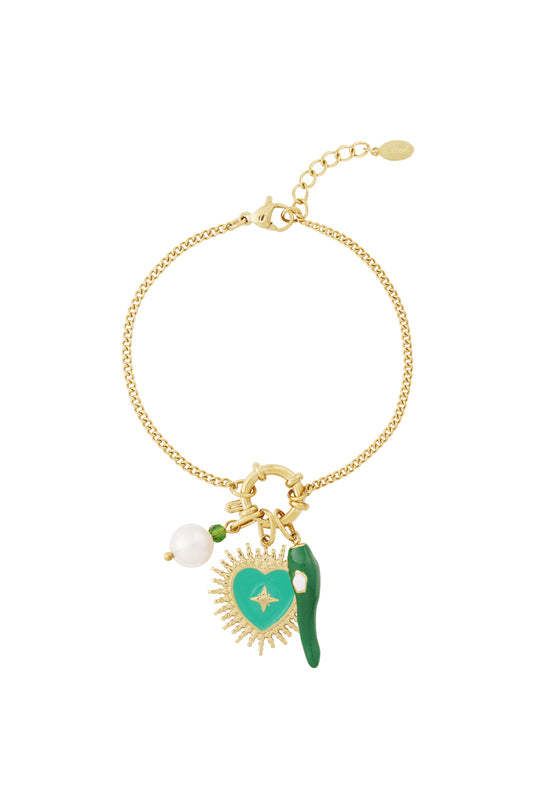 Gold charm bracelet with three charms attached - green enamel heart, pearl, and green chili pepper - laid flat on white background