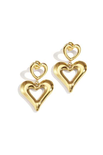 Pair of shiny gold double heart drop earrings on white background