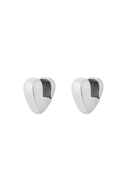 Pair of chunky silver heart-shaped hoop earrings with smooth polished finish isolated on white