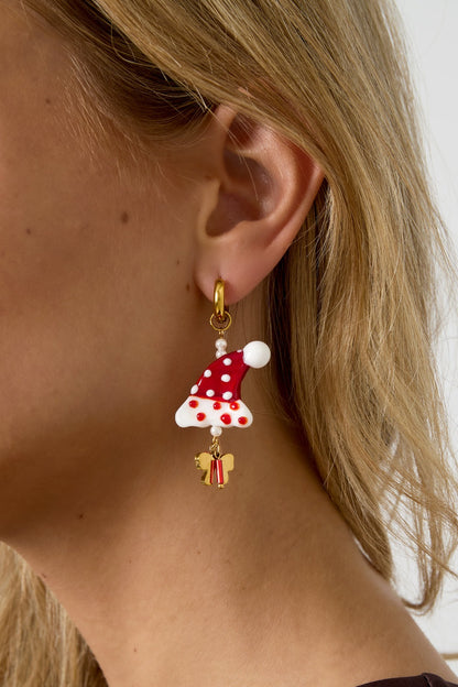 Close-up side view of a woman wearing a festive Santa hat drop earring with red, white, pearl, and gold details.