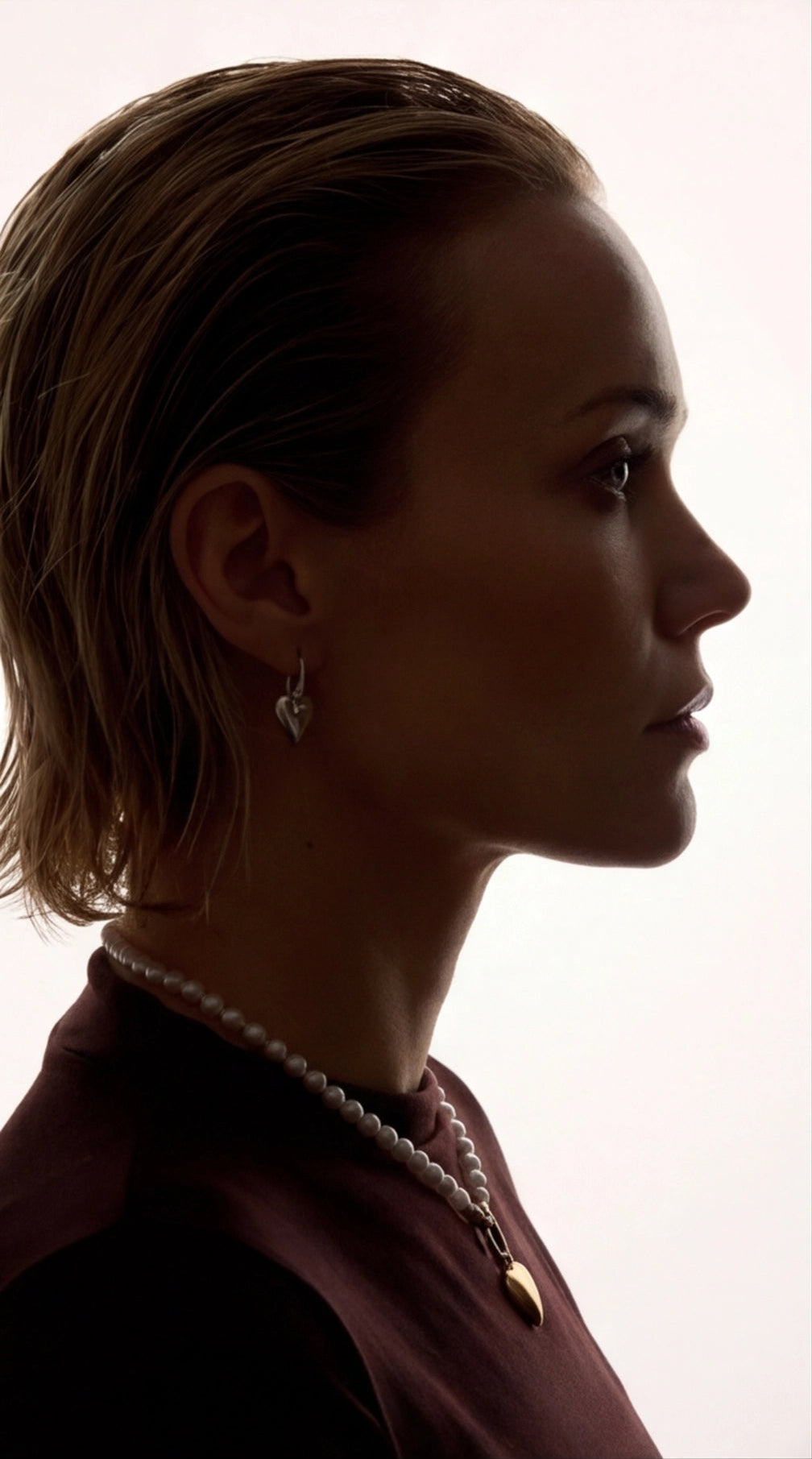 Silhouette of a woman wearing a pearl necklace against a white background