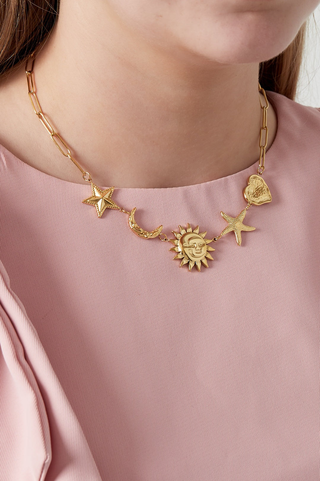 Model wearing gold celestial charm pendant necklace with pink top showing necklace detail