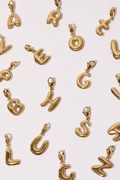 Flat lay of multiple gold tone alphabet charms scattered on light background