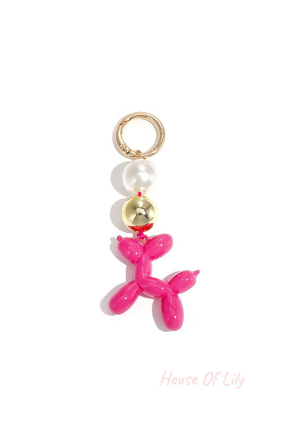 Bright pink balloon dog bag charm with pearl and gold beads on white background
