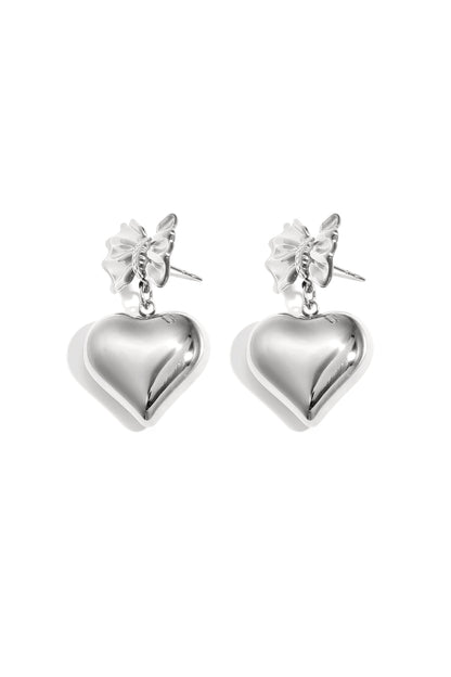 Silver version of bow and heart drop earrings shown on white background
