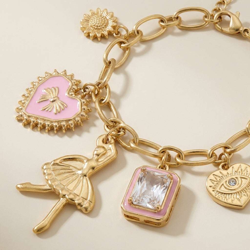 Gold chain charm bracelet featuring a ballet dancer, pink heart, rectangular crystal, sunflower, and evil eye charm.