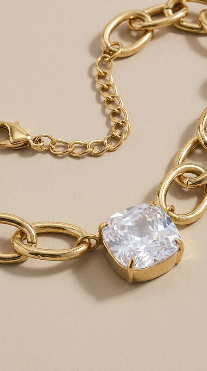 Retro Vibe Pendant: A gold-tone chunky chain necklace featuring a large, square-cut clear crystal pendant.
