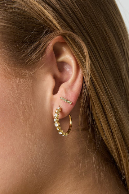Glitch Beam Studs: Gold bar earring with embedded crystals worn on an earlobe alongside a crystal-studded gold hoop.