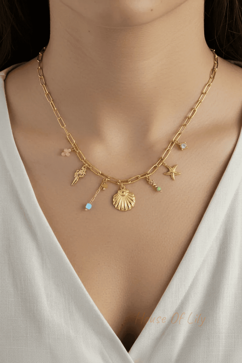 Gold-tone paperclip chain necklace with dangling shell, starfish, and colorful bead charms on a model.